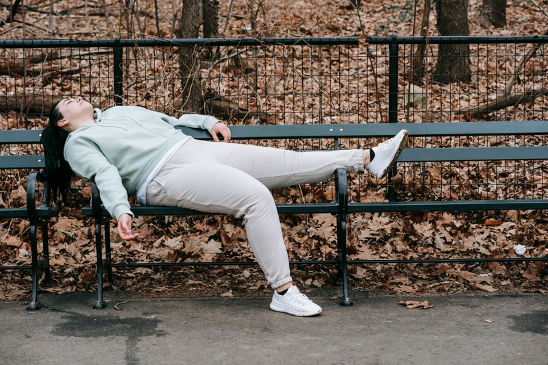 a woman lying on a public bench